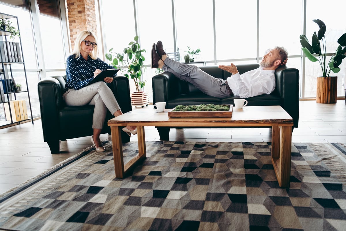 A businesswoman engages in a counseling session with a middle-aged client in a contemporary office, showcasing professional collaboration